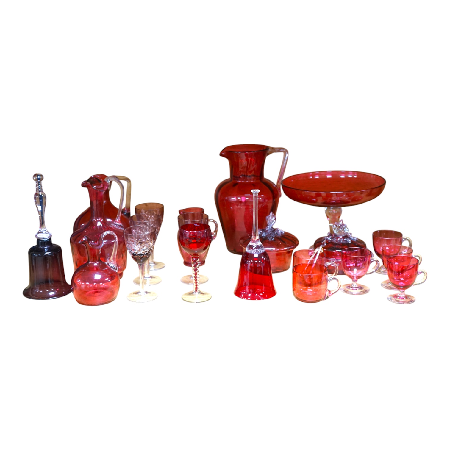 Mixed cranberry glassware to include jugs, glasses, jars and a comport, largest 23cm high. Condition - fair to good